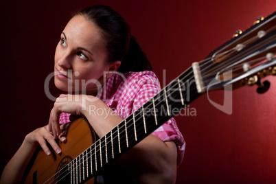 Frau hält klassischen Gitarre vor rotem Hintergrund