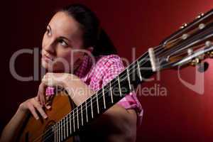 Frau hält klassischen Gitarre vor rotem Hintergrund