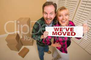 Goofy Couple Holding We've Moved Sign Surrounded by Boxes