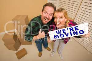 Goofy Couple Holding We're Moving Sign Surrounded by Boxes