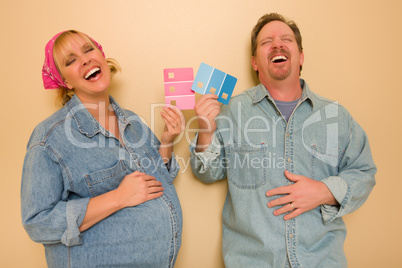 Pregnant Laughing Couple Deciding on Pink of Blue Wall Paint.