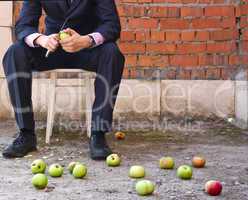 Businessman cleaning apples sitting on a stool