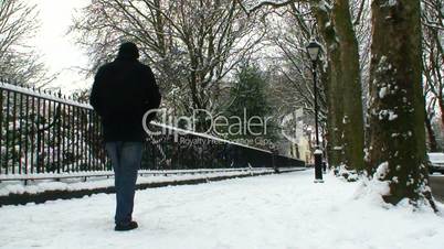 Man walking away from camera in snow covered street