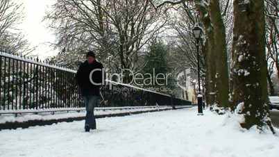 Man walking towards camera in snow covered street