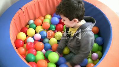 Little boy plays in ball pit