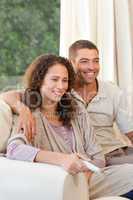 Couple watching tv in their living room at home