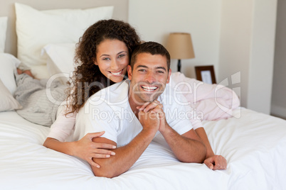 Pretty woman hugging her husband on their bed at home