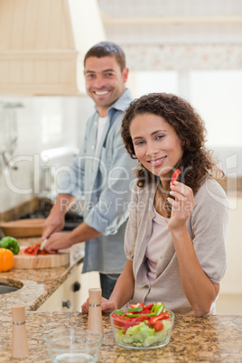 Woman eating while her husband is cooking