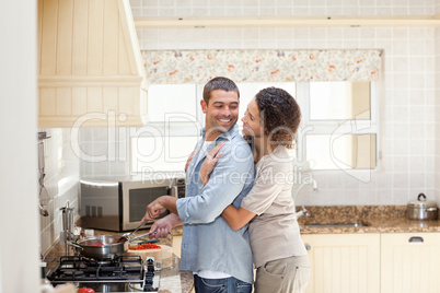 Woman hugging her husband while he is cooking