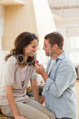 Lovers eating a strawberry in their kitchen