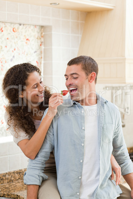 Lovers eating a strawberry in their kitchen