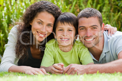Little boy with his parents lying down in the garden