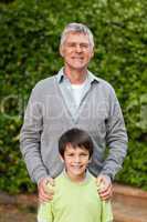 Grandfather with his grandson looking at the camera in the garde