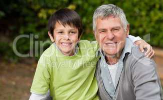 Grandfather with his grandson looking at the camera in the garde