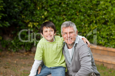 Grandfather with his grandson looking at the camera in the garde