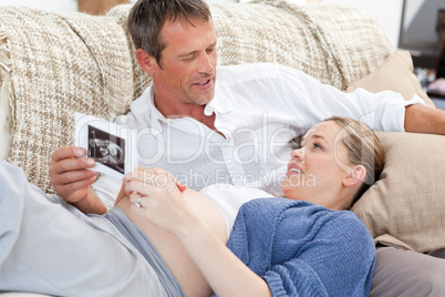 Couple looking at an X-ray on their couch at home