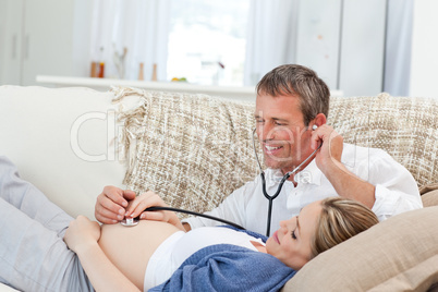 Man listening his wife's belly with his stethoscope