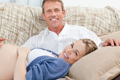 Happy pregnant woman with her husband on their sofa