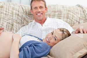 Happy pregnant woman with her husband on their sofa