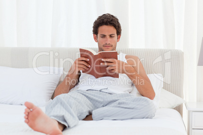 Man reading a book on his bed