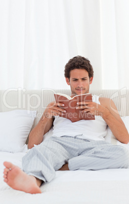 Man reading a book on his bed