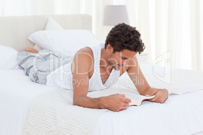 Man reading a book on his bed