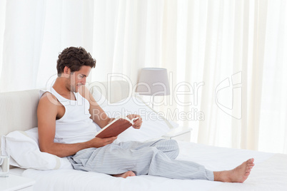 Man reading a book on his bed