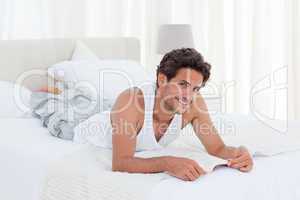 Man reading a book on his bed