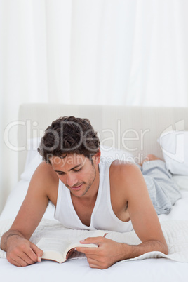 Man reading a book on his bed