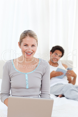 Woman working on her laptop while her husband is reading