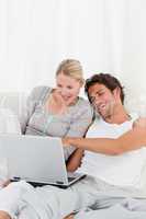 Adorable couple looking at their laptop on the bed