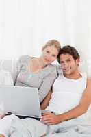 Adorable couple looking at their laptop on the bed