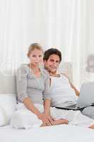 Adorable couple looking at their laptop on the bed