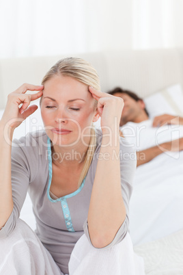 Attractive woman having a headache while her husband is sleeping