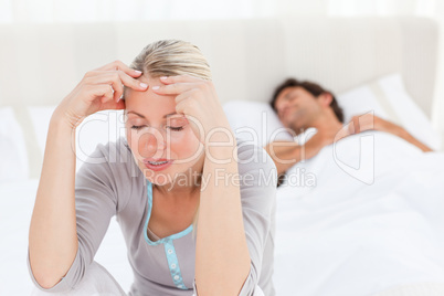 Attractive woman having a headache while her husband is sleeping