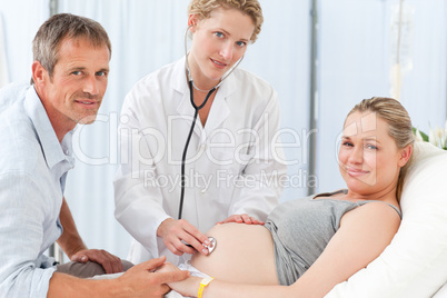 Pregnant woman with her husband and the nurse looking at the cam