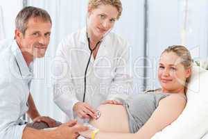 Pregnant woman with her husband and the nurse looking at the cam