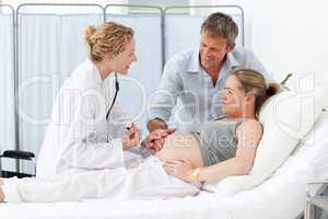 Pregnant woman with her husband listening to the nurse