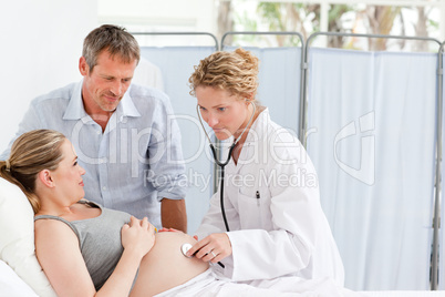 Pregnant woman with her husband listening to the nurse