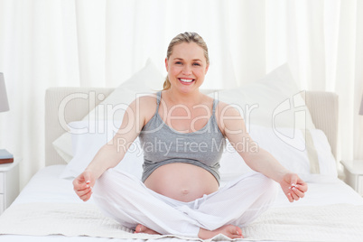 Pregnant woman practicing yoga on her bed