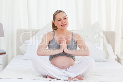 Pregnant woman practicing yoga on her bed