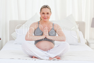 Pregnant woman practicing yoga on her bed