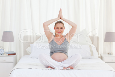 Pregnant woman practicing yoga on her bed