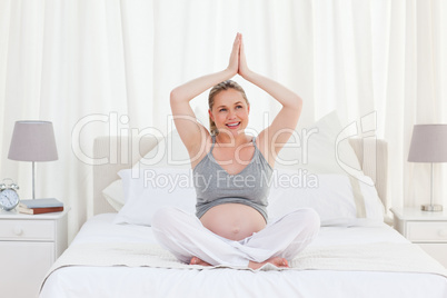 Pregnant woman practicing yoga on her bed