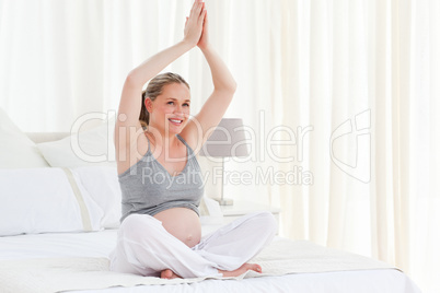 Pregnant woman practicing yoga on her bed