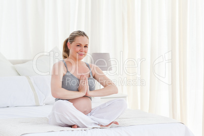 Pregnant woman practicing yoga on her bed