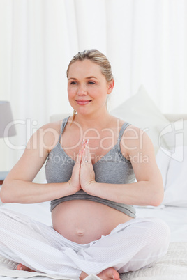 Pregnant woman practicing yoga on her bed