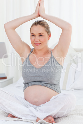 Pregnant woman practicing yoga on her bed