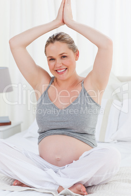 Pregnant woman practicing yoga on her bed