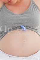 Pregnant woman with a baby dummy on her belly at home